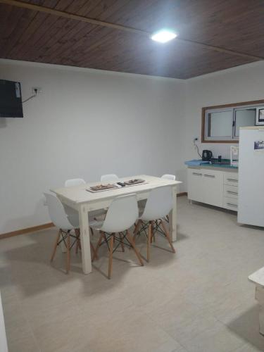 a kitchen with a white table and white chairs at CABAÑAS CHASCOMUS 2024 in Chascomús