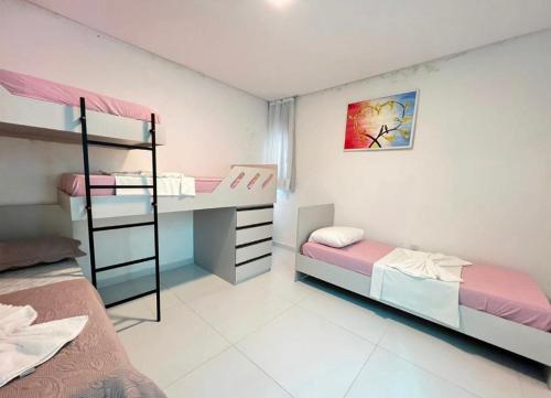 a bedroom with two bunk beds and a desk at Bela casa condominio beira mar praia dos carneiros in Tamandaré