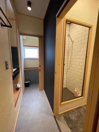 a bathroom with a walk in shower and a mirror at Yubaba House Downtown Apartments in Nozawa Onsen