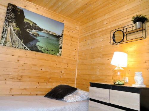 a bedroom with a wooden wall with a bed and a lamp at House by the lake in Wiselka in Wisełka