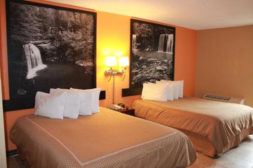 2 łóżka w pokoju hotelowym z pomarańczowymi ścianami w obiekcie Fairview Inn & Suite w mieście Jonesboro