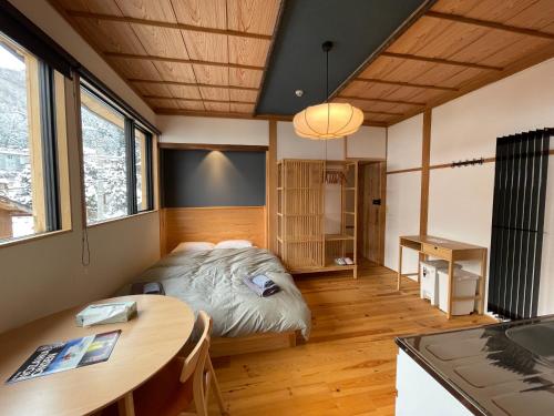 a bedroom with a bed and a table and a desk at Yubaba House Downtown Apartments in Nozawa Onsen