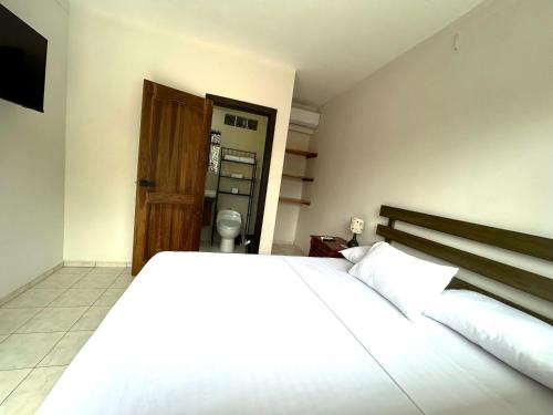 a bedroom with a white bed and a wooden door at OCEAN DRIVE LODGE in Montañita