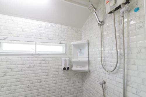 uma casa de banho branca com um chuveiro e um lavatório. em Rendezvous Oldtown Chiangmai SHA Extra Plus em Chiang Mai