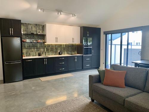ein Wohnzimmer mit einem Sofa und einer Küche in der Unterkunft Erowal Bay Guesthouse Jervis Bay in Erowal Bay