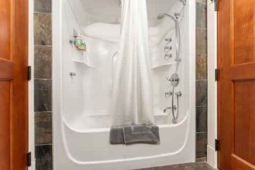 a bathroom with a bath tub with a shower at Solara Suite with Indoor Pool - Hot tub -Parking - GYM in Canmore