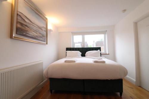 a bedroom with a bed with white sheets and a window at Garland Lovely Apartment, St John's Wood in London