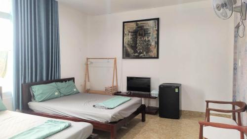 a room with two beds and a desk with a television at Q' Homestay Garden Villa in Hue