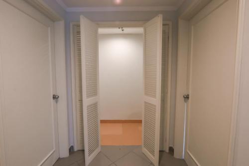 a hallway with white shuttered doors and a tile floor at Java Paragon Hotel & Residences in Surabaya