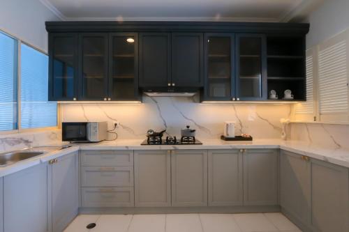 a kitchen with white counters and black cabinets at Java Paragon Hotel & Residences in Surabaya