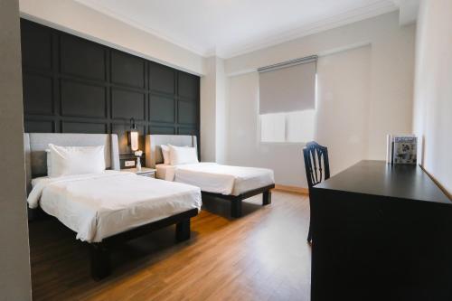 a hotel room with two beds and a desk at Java Paragon Hotel & Residences in Surabaya