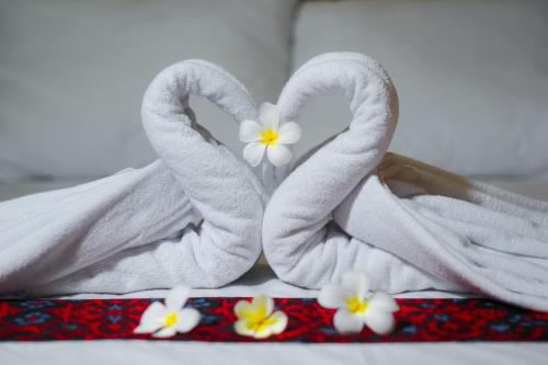 a couple of towels with flowers in them on a bed at Bello Bungalow in Batukliang