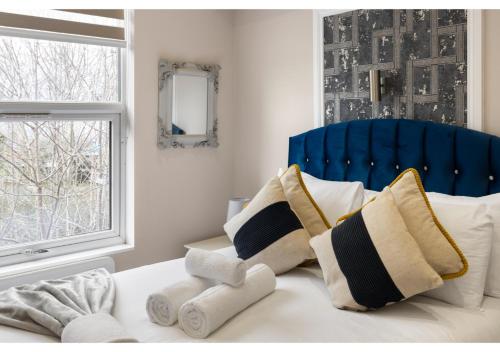 1 cama con cabecero azul y almohadas en Brand New Stunning and Cosy Studio - Very Central en Londres