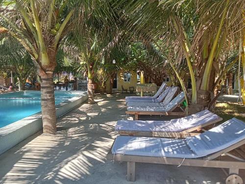 a row of chaise lounges next to a pool with palm trees at Biển Ngọc Homstay in Ấp Sung Xuân