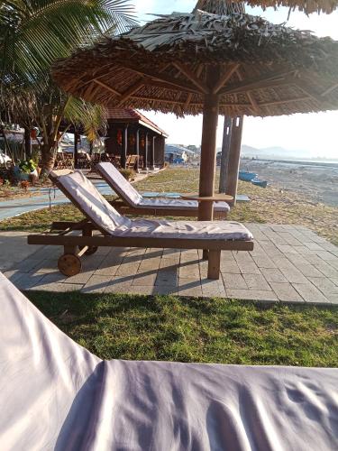 two lounge chairs under an umbrella on the beach at Biển Ngọc Homstay in Ấp Sung Xuân