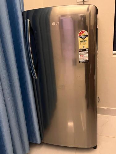 a stainless steel refrigerator sitting next to a blue curtain at Chaithanya Residency Near to NIT in Kunnamangalam