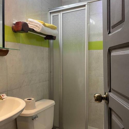 a bathroom with a shower and a toilet and a sink at Calu L' Petit Hostel in Quito