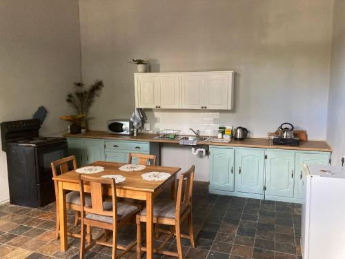une cuisine avec une table en bois, des chaises et un comptoir dans l'établissement Just-a-bed - Stone Cottage, à Graaff-Reinet