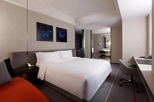 a hotel room with a large white bed and a desk at Humble House Taipei, Curio Collection by Hilton in Taipei