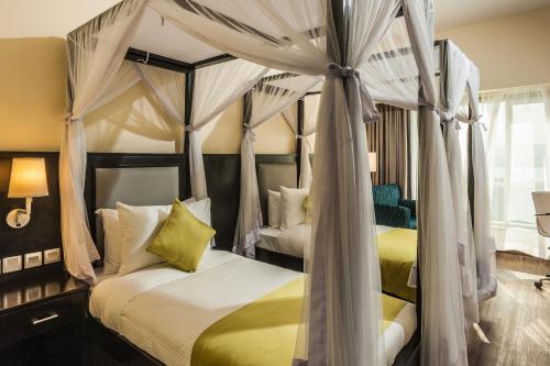1 dormitorio con 2 camas con cortinas en Acacia Premier Hotel, en Kisumu