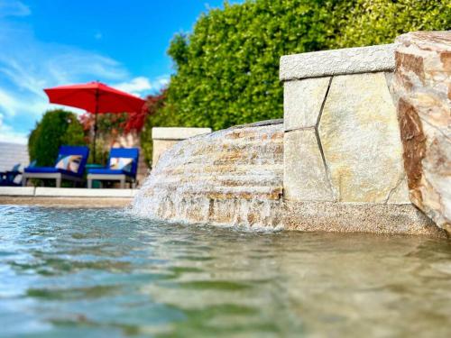 una fuente de agua con sillas y una sombrilla en NEW! The Blue Cactus - Pool, Spa, Game Room, en Palm Springs