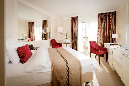 um quarto de hotel com uma grande cama branca e cadeiras vermelhas em Park Hotel Sonnenhof - Relais & Châteaux em Vaduz