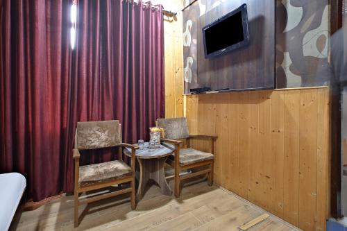 OYO Hotel Azad في جامو: غرفة بها كرسيين وطاولة وتلفزيون