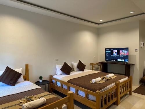 a bedroom with two beds and a flat screen tv at Suntalee House in Nai Yang Beach