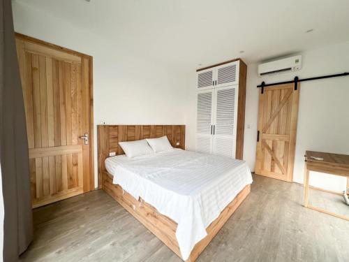 a bedroom with a large bed and a wooden door at VILLA VENUS -Khu B Không mất vé cổng - tại Khu du lịch sinh thái Đại Lải in Thanh Cao