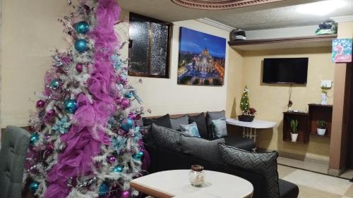 una sala de estar con un árbol de Navidad púrpura en Departamento céntrico y cerca del foro sol, en Ciudad de México