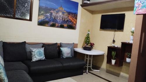 ein Wohnzimmer mit einem schwarzen Sofa und einem Tisch in der Unterkunft Departamento céntrico y cerca del foro sol in Mexiko-Stadt