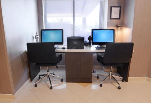 una oficina con dos monitores y dos sillas y un escritorio en SpringHill Suites Dulles Airport en Sterling