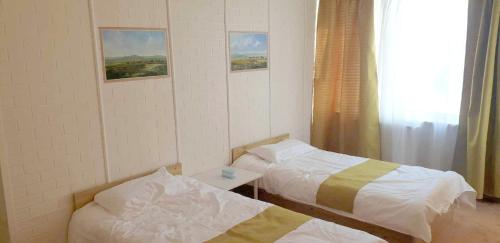 a room with two beds and a table and a window at Gandan Terrace Guesthouse in Ulaanbaatar
