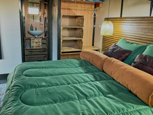 Cama en habitación con edredón verde grande en TINY EL ZAPATO en Suesca