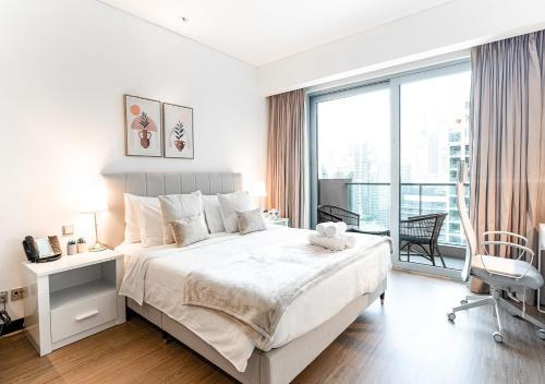 a white bedroom with a large bed and a window at 5-Star Studio at The Address Marina, Mall Access in Dubai