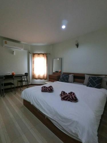 a bedroom with a large white bed with towels on it at Alongkorn hotel by SB in Samut Songkhram