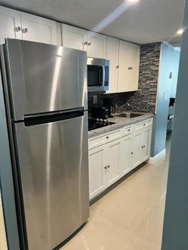 a stainless steel refrigerator in a kitchen with white cabinets at Entire Condo in Sunny Isles in Sunny Isles Beach