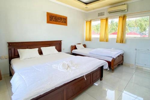 een slaapkamer met 2 bedden en handdoeken bij Puri Karimunjawa RedPartner in Karimunjawa