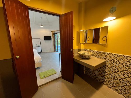 een badkamer met een wastafel en een kamer met een bed bij The Little Clay House (Huahin) in Ban Thap Tai (1)