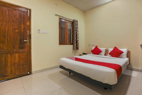 - une chambre avec un lit doté d'oreillers rouges et d'une porte dans l'établissement Om Sakthi Hotel, à Pondichéry