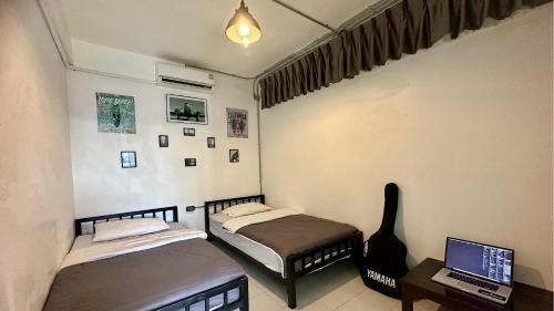 a room with two beds and a laptop on a desk at Backpack Hostel in Chiang Rai