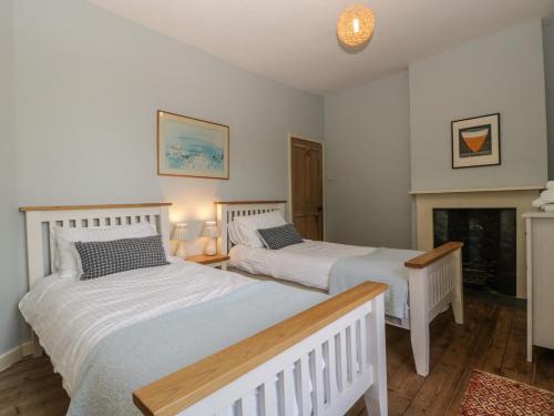 two beds in a room with a fireplace at Woodlands Cottage in Leominster