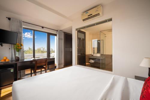 1 dormitorio con 1 cama blanca grande y escritorio en RAON Hoian Beach en Hoi An