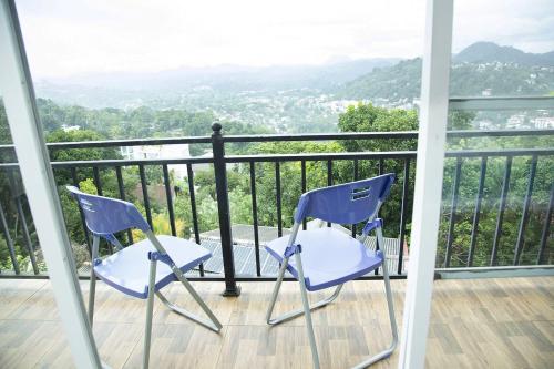 dwa krzesła siedzące na balkonie z widokiem w obiekcie Eden Rock Luxurious Accommodation w mieście Kandy