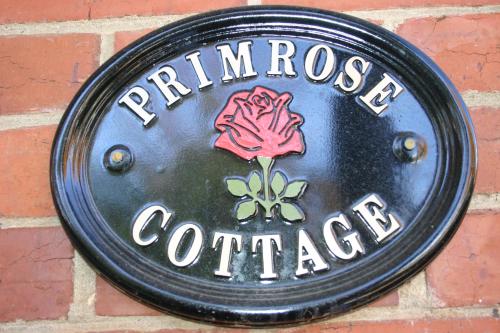 a sign on a brick wall with a rose on it at Primrose Cottage in Albury