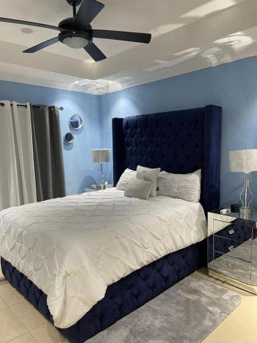 - une chambre bleue avec un grand lit et un ventilateur de plafond dans l'établissement Alexia's Stay, à Portmore