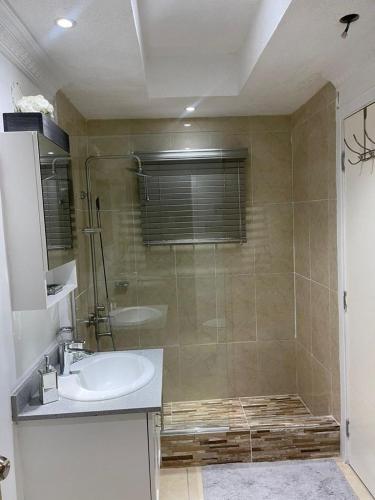 a bathroom with a shower and a sink and a tub at Alexia's Stay in Portmore