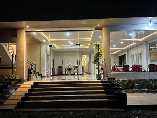 a lobby of a building with stairs and chairs at Grands Orchid Hotel in Lahat