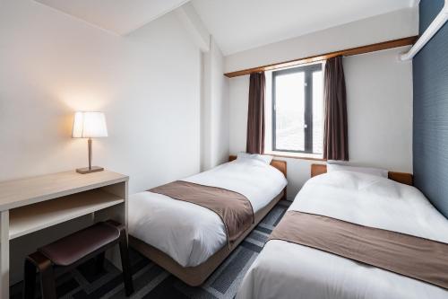 a hotel room with two beds and a desk at Auberge Amanohashidate in Miyazu