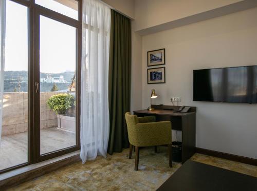 ein Hotelzimmer mit einem Schreibtisch und einem großen Fenster in der Unterkunft Citrus Hotel in Tbilisi City